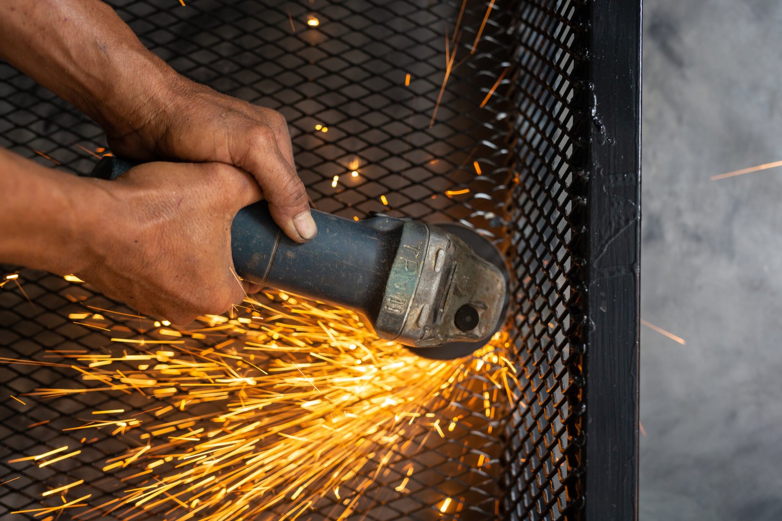 Male workers cut and weld metal with spark.